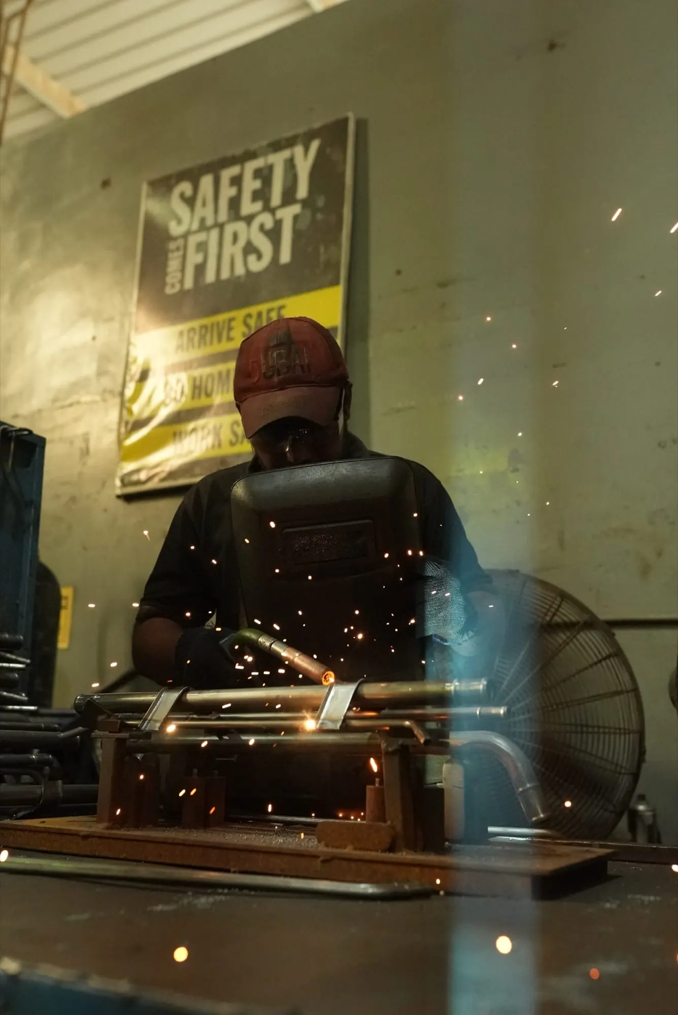 Sparks flying as a welder MIG welds a pipe assembly held in a fixture