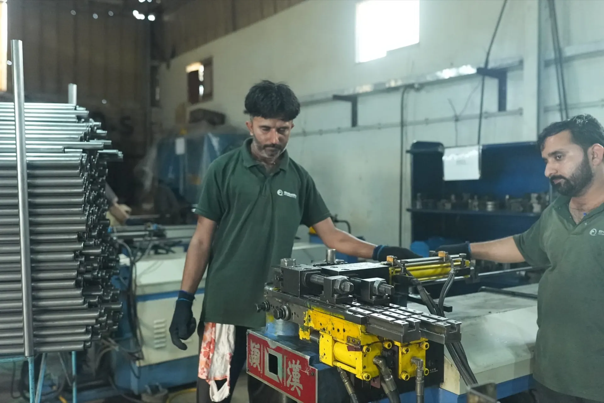 Two operators working together at a hydraulic pipe bending machine