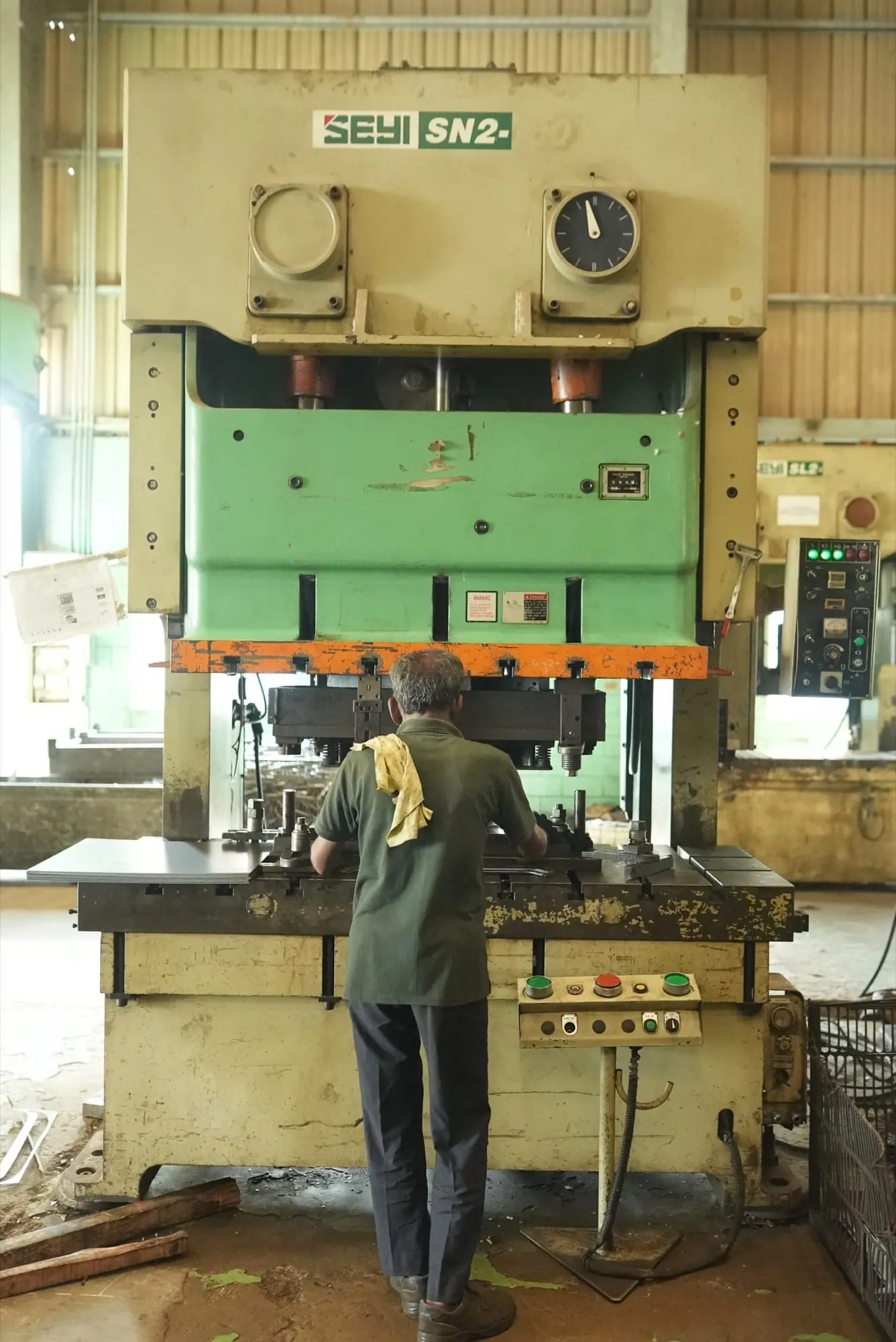 Operator positioning a sheet metal blank in the die of a double-crank press