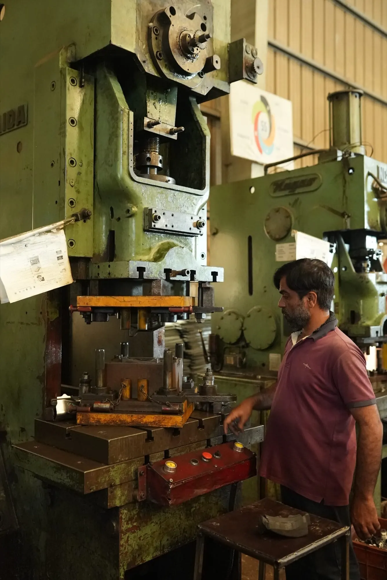 Press operator at the controls of a mechanical press fitted with a progressive die